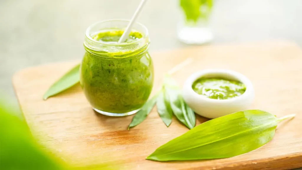 Frisches Bärlauchpesto im Glas mit frischen Bärlauchblättern auf einem Holzbrett – einfaches Rezept für selbstgemachtes Bärlauchpesto