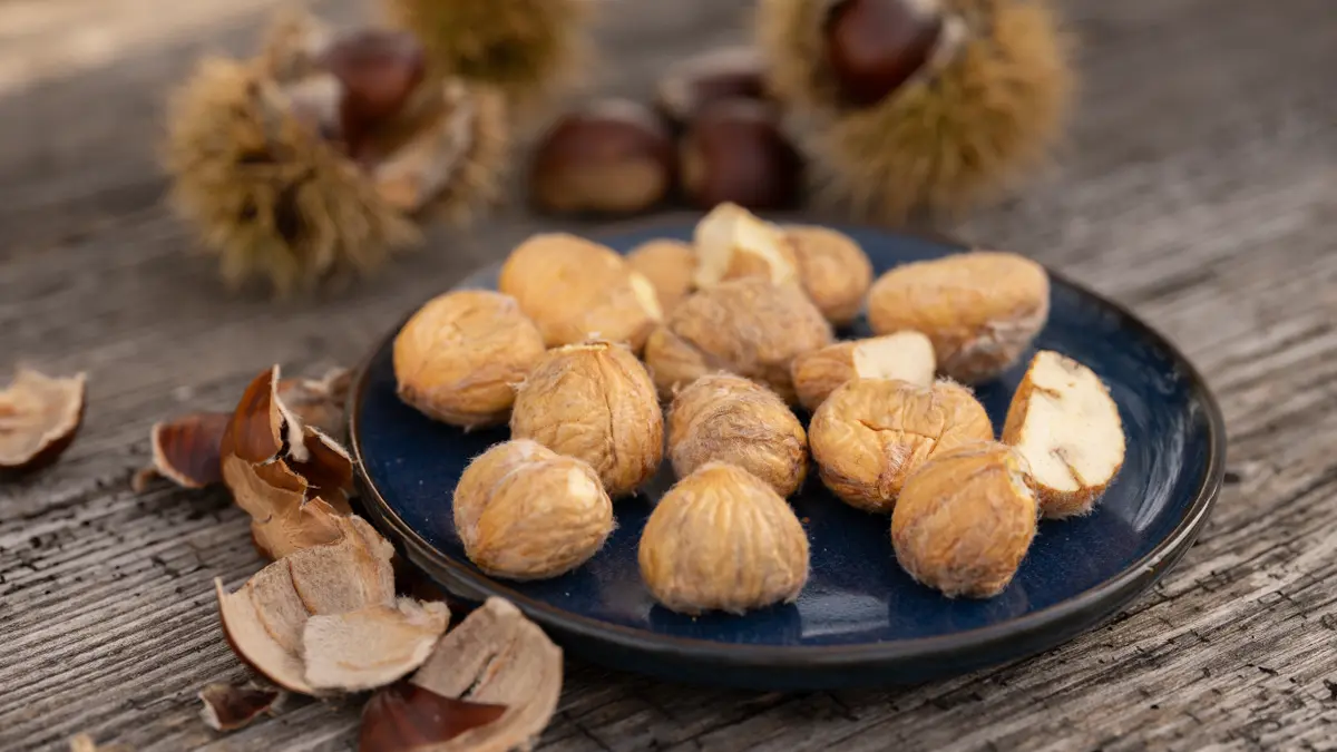 Frische Maronen und Esskastanien im Oktober auf rustikalem Holztisch – herbstliche Beilage und Rezeptidee