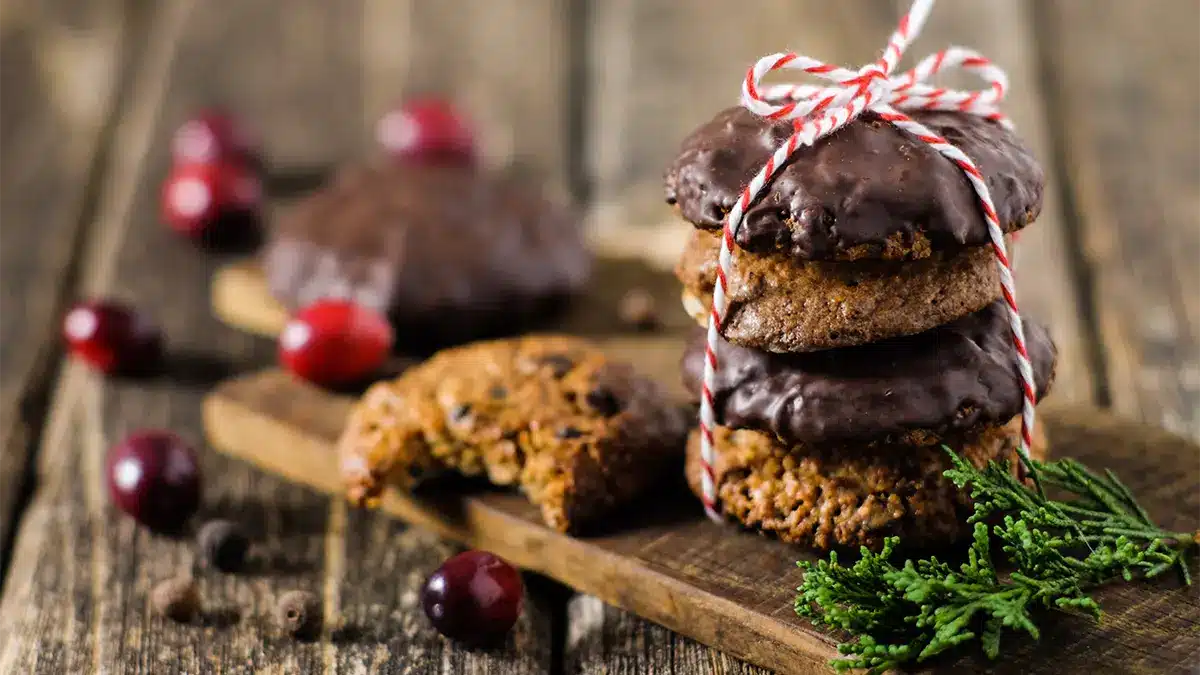 Saftige Lebkuchen ohne Zucker auf rustikalem Holztisch, weihnachtlich dekoriert mit Beeren und Gewürzen