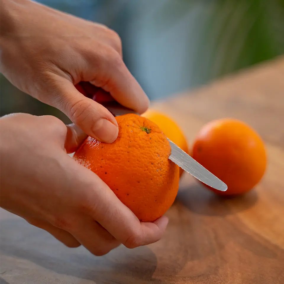 Frau schneidet Orange für das Dressing
