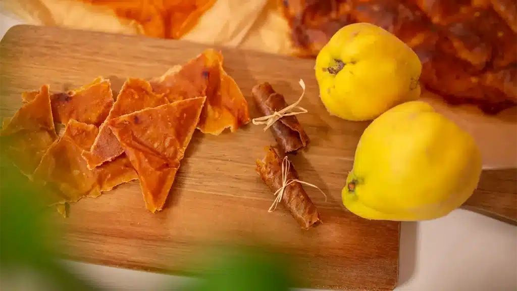Hausgemachtes Quitten-Fruchtleder auf einem Holzbrett mit frischen Quitten – gesunder Snack aus der Herbsternte
