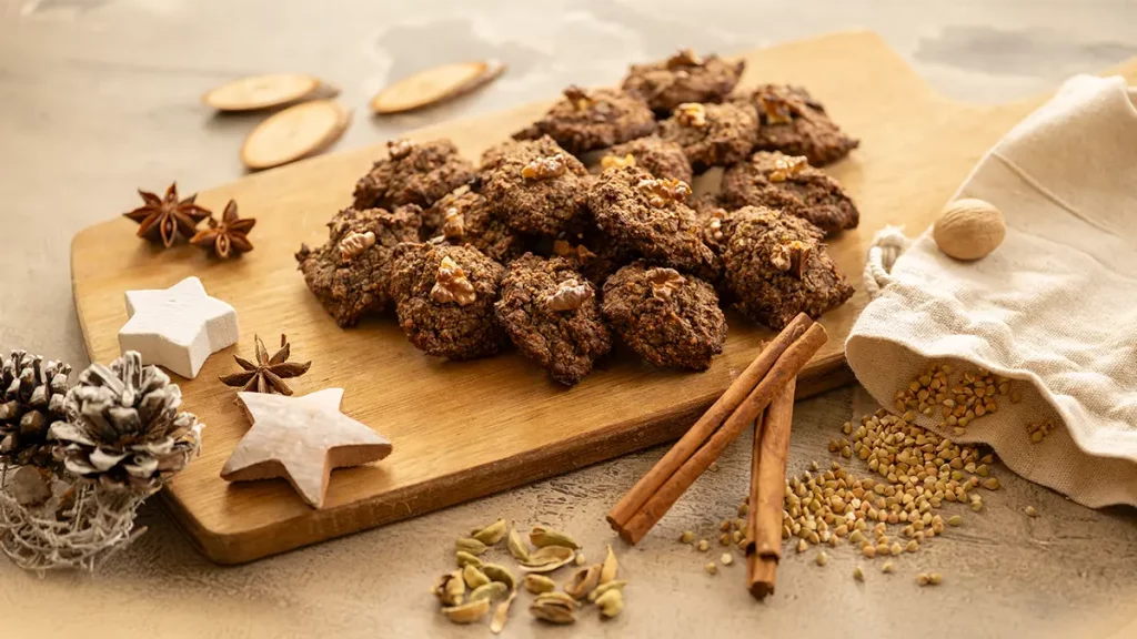 Gesunde Gewürzplätzchen auf einem Holzbrett, weihnachtlich dekoriert mit Zimtstangen und Sternanis